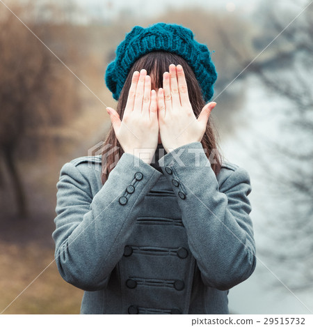 young pretty girl with hands over eyes outdoors 29515732
