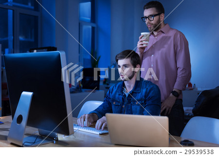 Serious clever man standing behind his colleague Serious clever man standing behind his colleague 29539538