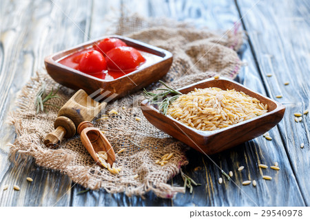 Italian pasta Orzo and tomatoes in wooden bowls. Italian pasta Orzo and tomatoes in wooden bowls. 29540978