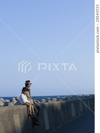 Father and son sitting on a breakwater 29543555
