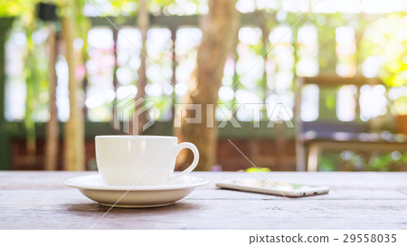 Hot coffee and smartphone on a wooden table. Hot coffee and smartphone on a wooden table. 29558035