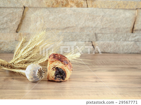 Sweet roll lies on table with poppy head spikelets 29567771