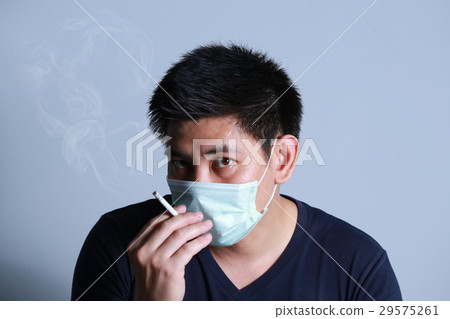 young man smoking cigarette with protective mask young man smoking cigarette with protective mask 29575261