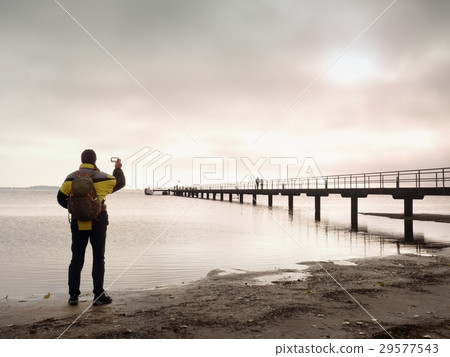 Hiker with backpack alone on beach, sea bridge. Hiker with backpack alone on beach, sea bridge. 29577543