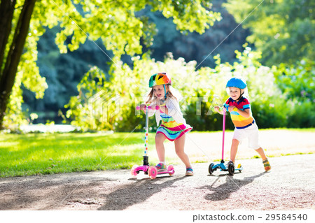 圖庫照片: kids riding scooter in summer park.