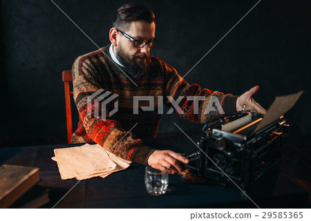 Bearded poet in glasses typing on typewriter 29585365