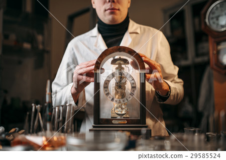 Watchmaker holding old table clock 29585524