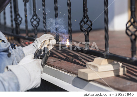 A worker welding metal handrails on the stairs A worker welding metal handrails on the stairs 29585940