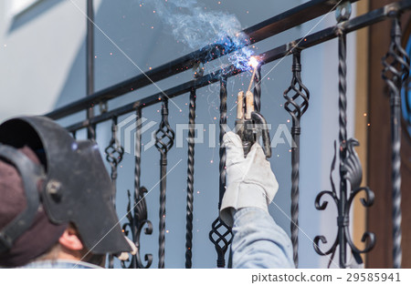 A worker welding metal handrails on the stairs 29585941