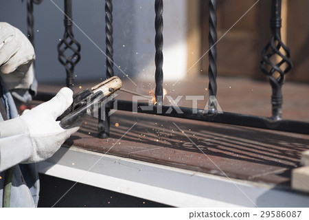 A worker welding metal handrails on the stairs A worker welding metal handrails on the stairs 29586087