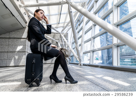 A woman sitting on a carry bag A woman sitting on a carry bag 29586239