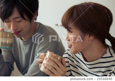 A couple in their twenties who is relaxing while drinking coffee at a cafe 29588640
