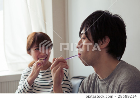 A couple in their twenties brushing their teeth in a room 29589214
