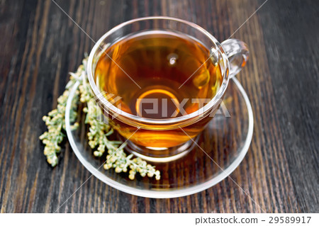 Tea with gray wormwood in glass cup on dark board 29589917