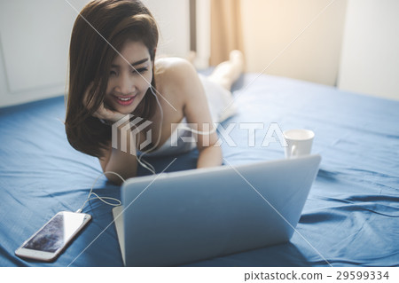 woman using laptop on the bed woman using laptop on the bed 29599334