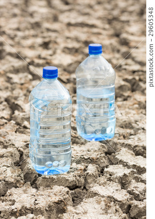 Bottle with water on the dried ground. Global Bottle with water on the dried ground. Global 29605348
