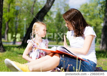 girl and a young woman reading a book together girl and a young woman reading a book together 29608345