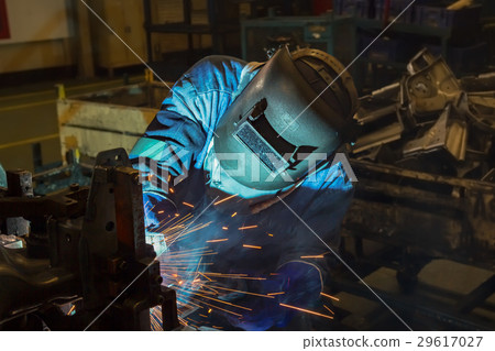 Worker is welding automotive part in car factory 29617027