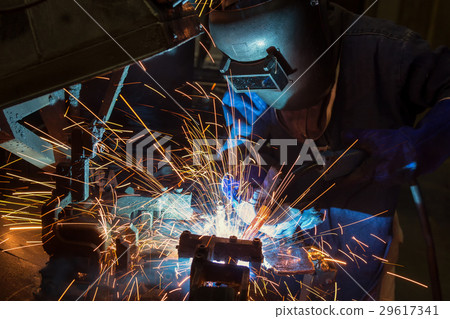 Worker is welding in car factory 29617341
