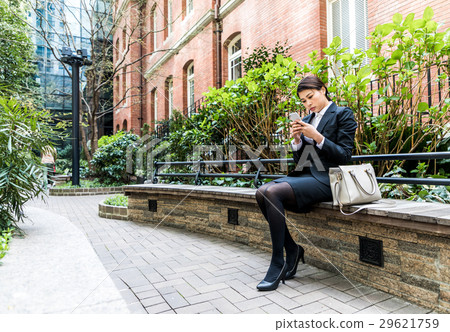 A woman using a smartphone in a park 29621759