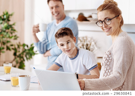 Cheerful mother helping her son with homework Cheerful mother helping her son with homework 29630841