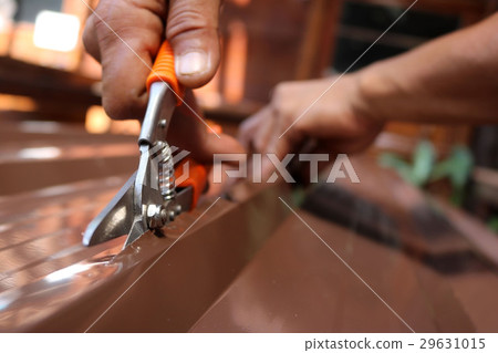Workers use scissors to cut the metal sheet. 29631015