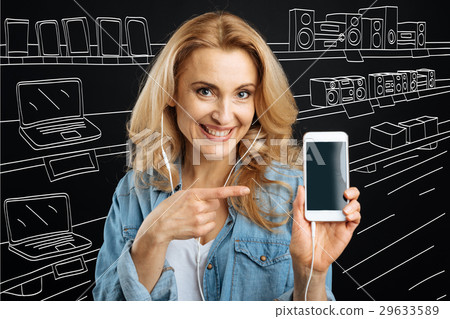 Happy blonde woman pointing at her smartphone Happy blonde woman pointing at her smartphone 29633589