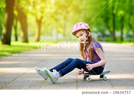 Cute little preteen girl wearing helmet sitting on a skateboard Cute little preteen girl wearing helmet sitting on a skateboard 29634757