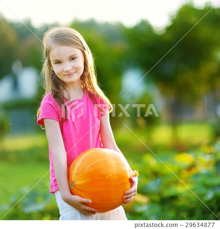 Cute little girl holding a pumpkin 29634877
