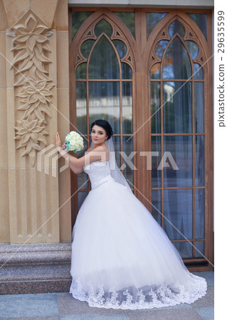 Bride with a bouquet is near the window Bride with a bouquet is near the window 29635599