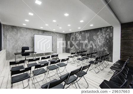 Room for lecture with a lot of dark chairs. Walls 29637663