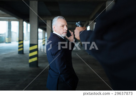 Unhappy cheerless businessman looking at the gun Unhappy cheerless businessman looking at the gun 29637873
