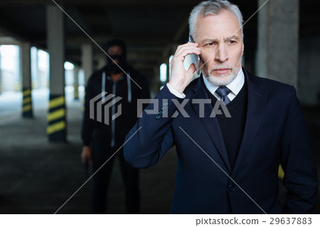 Serious grey haired businessman putting his phone Serious grey haired businessman putting his phone 29637883