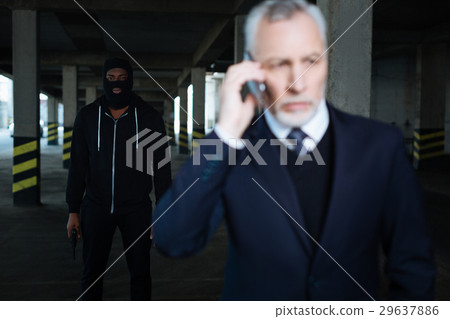 Serious male kidnapper wearing a mask Serious male kidnapper wearing a mask 29637886
