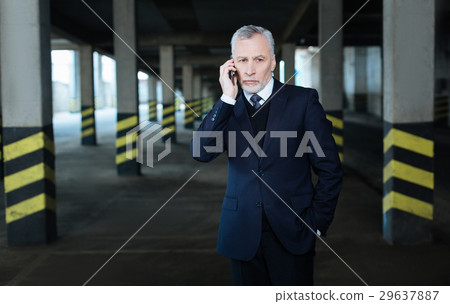 Serious nice businessman holding his smartphone Serious nice businessman holding his smartphone 29637887
