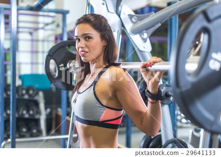 Fit woman doing squats with the barbell Smith 29641133