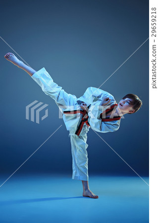 Young boy training karate on blue background Young boy training karate on blue background 29659218