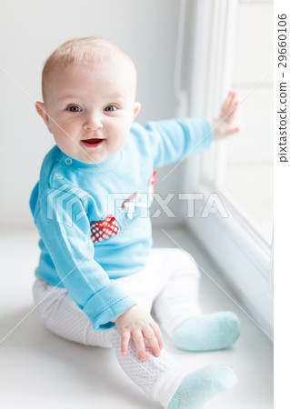Laughing baby sitting on the windowsill 29660106