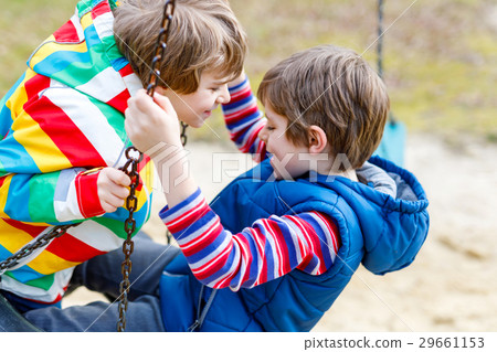 Two little kid boys having fun with chain swing on Two little kid boys having fun with chain swing on 29661153