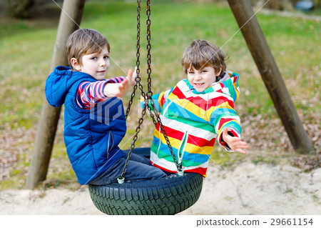 Two little kid boys having fun with chain swing on Two little kid boys having fun with chain swing on 29661154
