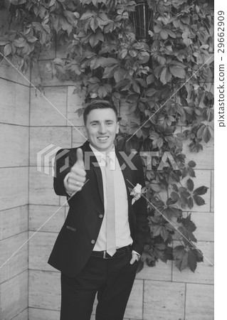 Groom in a stylish suit against a brick wall background Groom in a stylish suit against a brick wall background 29662909