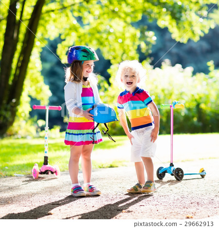 Kids riding scooter in summer park. Kids riding scooter in summer park. 29662913