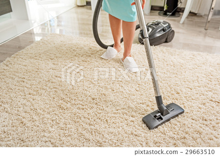 Female person carefully hoovering room 29663510