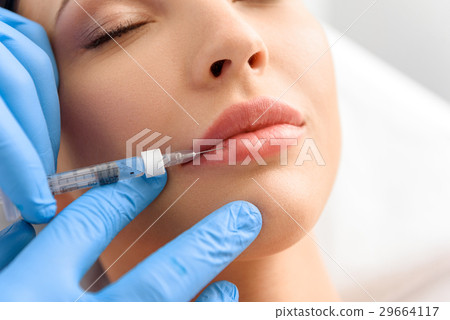 Serene woman enduring ache from syringe in clinic Serene woman enduring ache from syringe in clinic 29664117