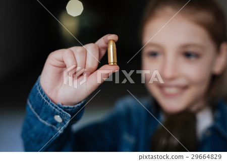 Selective focus of a bullet being held by a girl 29664829