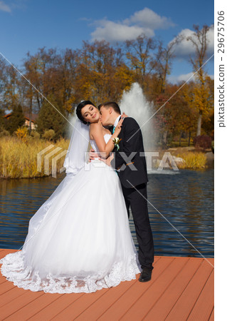 The groom tenderly kisses the bride in the neck standing on the pier The groom tenderly kisses the bride in the neck standing on the pier 29675706