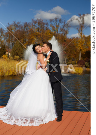 The groom tenderly kisses the bride in the neck standing on the pier The groom tenderly kisses the bride in the neck standing on the pier 29675707