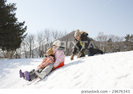 A father playing with a sled 29676343