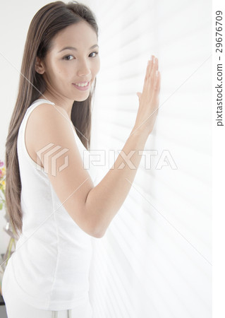 A young woman putting his hand on the blind 29676709