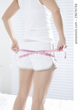 A young lady measuring a hip with a measuring tape A young lady measuring a hip with a measuring tape 29676788